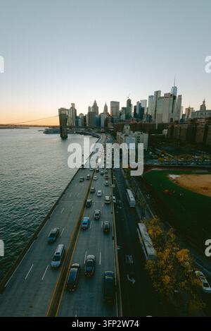 New York, Vereinigte Staaten - 05. Oktober 2026: Luftaufnahme der Brooklyn Bridge und der Skyline von Manhattan bei Sonnenuntergang, mit Verkehr auf der FDR Drive und einem Baseball Stockfoto