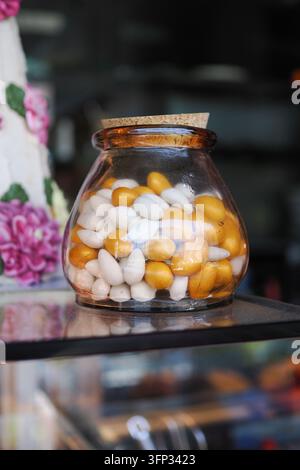 Gläsernes Glas gefüllt mit gelben und weißen Süßigkeiten in einer Ladenauslage Stockfoto