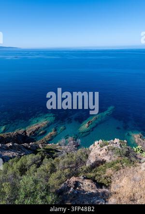 Klares Türkis und tiefblaues Meer mit Unterwasserfelsen, gesehen von einem Küstenhügel aus, Korsika, Frankreich Stockfoto
