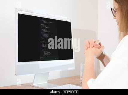 Künstliche Intelligenz-Chatbot-Code auf dem Monitor, Frau umklammert ängstlich die Hände und beobachtet die KI-Aufforderungsergebnisse. Generativer KI-Assistent und hine-Lernsc Stockfoto