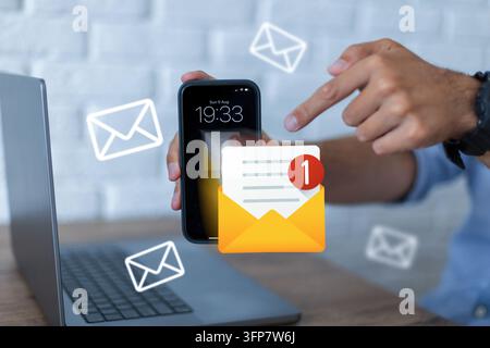 Mann hält ein Smartphone mit einer Benachrichtigungssymbol für ungelesene E-Mails auf dem Bildschirm und zeigt mit dem Finger. E-Mail-Marketing, digitale Kommunikation und Online Stockfoto