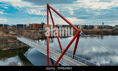Moderne rote Fußgänger-Hohlkastenbrücke über Wasser in einem städtischen Park Stockfoto