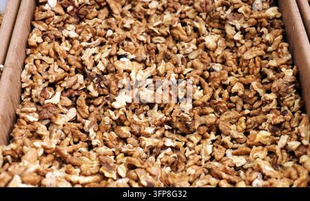 Haufen von geschälten Walnuss-Hälften und -Stücken, die eine rustikale braune Textur und nährstoffreiches, proteinreiches Nussfleisch zeigen, ideal für gesunde Snacks, Backwaren, Beläge, Stockfoto
