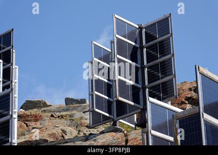Detail von Solarmodulen in den Bergen vertikal montiert wie vier Flügel um eine zentrale Säule wie ein Baum, Photovoltaikanlage vermeidet Schneianhäufung, Zukunft Stockfoto