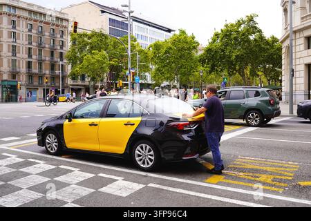 BARCELONA, SPANIEN – 23. AUGUST 2026: Gelbes und schwarzes Taxi, das in der belebten Innenstadt mit Fußgängern geparkt ist Stockfoto