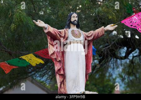 Verwitterte Statue des Heiligstes Herzens Jesu mit Papel Picado, alter Friedhof, Monterrey, Mexiko Stockfoto
