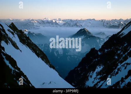 Ein atemberaubender Blick fängt die schneebedeckten Gipfel der Mont-Blanc-Kette ein, die in sanftem Morgenlicht baden. Die Szene zeigt eine weite Ausdehnung von Bergen Stockfoto