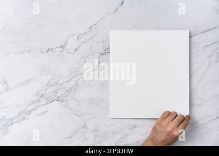 Oberblick-Sequenz von offen bis geschlossen, leeres weißes Grußkarten-Modell auf Marmorhintergrund mit Kopierraum: Hand öffnet eine leere weiße gefaltete Grußkarte Stockfoto