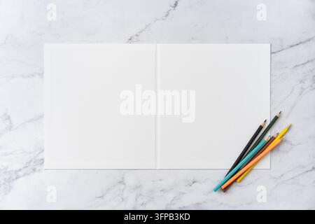 Ansicht von oben von offen zu geschlossen, leerer weißer Grußkarten-Mockup auf Marmorhintergrund mit Platz für Text: farbige Stifte auf geöffnetem leerem weißem Gruß Stockfoto