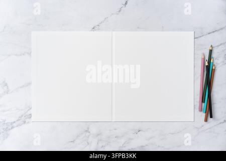 Ansicht von oben von offen zu geschlossen, leerer weißer Grußkarten-Mockup auf Marmorhintergrund mit Platz für Text: farbige Stifte auf geöffnetem leerem weißem Gruß Stockfoto