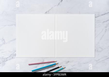 Ansicht von oben von offen zu geschlossen, leerer weißer Grußkarten-Mockup auf Marmorhintergrund mit Platz für Text: farbige Stifte auf geöffnetem leerem weißem Gruß Stockfoto