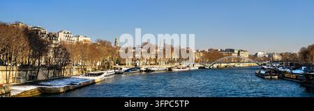 Panoramablick auf die Seine mit festgemachten Booten, der Passerelle Debilly und der Uferarchitektur an einem sonnigen Wintertag in Paris, Frankreich. Stockfoto