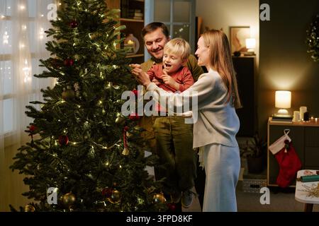 Familie mit Kind schmückt den Weihnachtsbaum zu Hause Stockfoto
