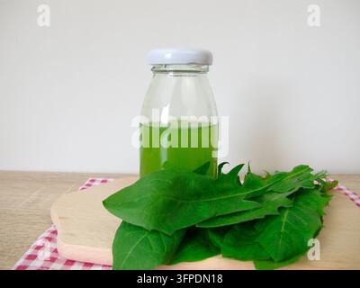 Eine Flasche frisch gepresster Löwenzahnsaft aus frischen Löwenzahnblättern Stockfoto