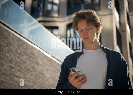 Verärgerter junger Mann liest Nachricht auf dem Smartphone Stockfoto
