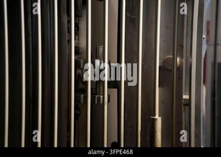 Nahaufnahme eines massiven Stahlsafenschranktors mit dicken vertikalen Schließbolzen und Sicherheitsmechanismus-Hardware. Stockfoto