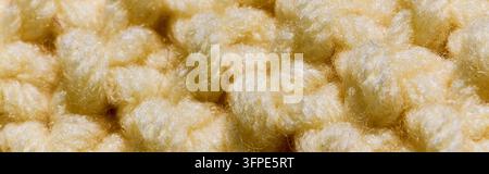 Zarte Texturen eines gestrickten buttergelben weichen Pullovers im Makro, Banner Stockfoto