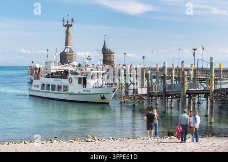 Das Passagierschiff Seagull segelt am Kai entlang, während Besucher und ein Hund vom Ufer aus zuschauen, Hafen mit der Imperia-Statue, Konstanz am Bodensee Stockfoto
