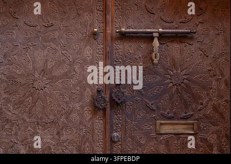 Marokko, eine Tür mit Holzschnitzereien und Türklopfern in der Altstadt von Marrakesh in einem Riad Stockfoto