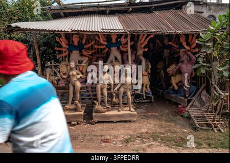 Durga Puja beeinflusst die Wirtschaft, Kultur und Umwelt von Westbengalen erheblich. Die Göttinnen-Durga-Idole werden durch einen traditionellen Tonbildhauprozess gefertigt, der Monate vor dem Fest beginnt. Kunsthandwerker verwenden Schwemmland aus Flussbetten (hier der Jalngi-Fluss), schichten es auf eine Strohstruktur, um den Sockel der Statue zu bilden. Die Idole werden dann in Werkstätten innerhalb der Töpferkolonie im Rahmen der Festvorbereitungen bemalt. Wegen des Zeitdrucks und des Mangels an Kunsthandwerkern nehmen alle in der Töpferkolonie, einschließlich verheirateter Frauen und Kinder, die normalerweise nicht an suc Stockfoto