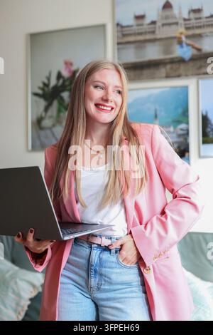 Selbstbewusster Freiberufler mit Laptop zu Hause, der flexible Arbeit, Unabhängigkeit und digitale Karrieremöglichkeiten veranschaulicht. Stockfoto