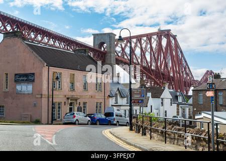 Die historische Forth Bridge, die über die Main Street und das Ferrybridge Hote in North Queensferry, Fife, Schottland ragt Stockfoto