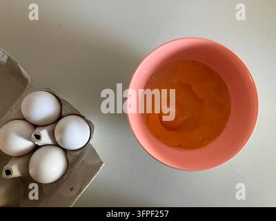 Eier in einer rosa Schüssel mit Eierkarton auf weißer Arbeitsplatte Stockfoto