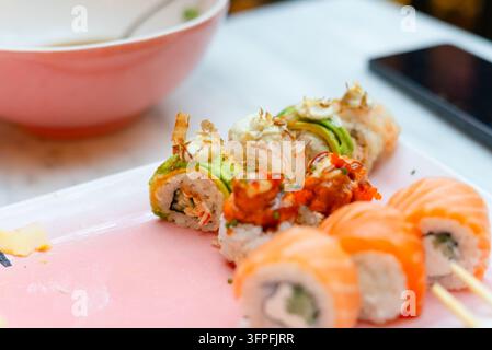 Gourmet-Sushi-Rollen wunderschön auf einem Teller in einem Restaurant serviert. Japanisches Komfortessen mit Sorgfalt arrangiert für eine sättigende Mahlzeit. Köstliche Maki, die das Beste der traditionellen Meeresfrüchte-Küche präsentieren Stockfoto