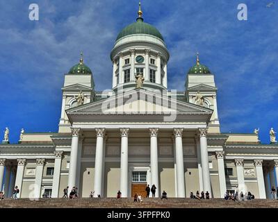 Nahaufnahme der neoklassizistischen Fassade der Kathedrale von Helsinki, grüne Kuppeln und korinthische Säulen, mit Besuchern auf den Stufen in Helsinki, Finnland. Stockfoto