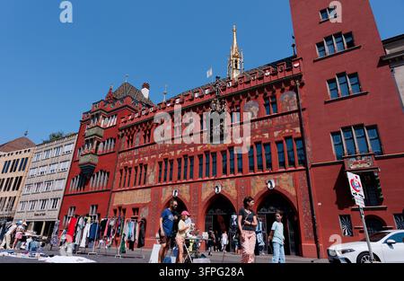 Vergoldeter Turmspitze und freskierte rote Fassade des Basler Rathauses erheben sich über einem sonnigen Flohmarkt auf dem Marktplatz Stockfoto