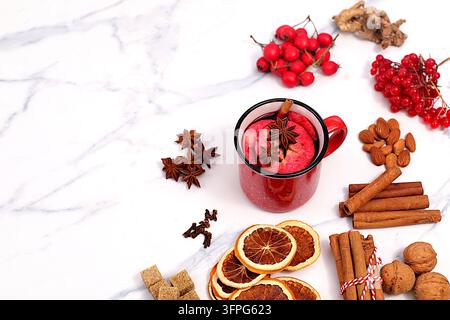 Heißer Glühwein in einem Eisenbecher mit Gewürzen, gebranntem Zucker, Nelken, Nüssen, Zimt, Sternanis, Ebereschenbeeren und Hagebutten, abstrakte Herbststillleben c Stockfoto