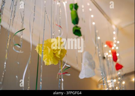 Festliche Partydekorationen mit bunten Papierblumen, Bändern und Lichterketten Stockfoto