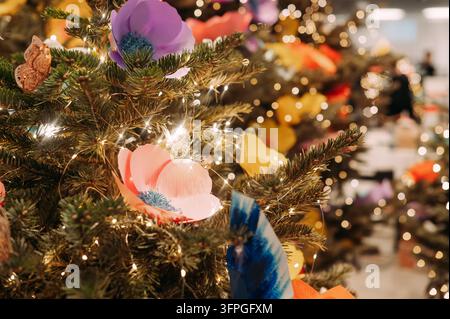 Weihnachtsbaum mit bunten Blumenornamenten und leuchtenden Lichtern Stockfoto