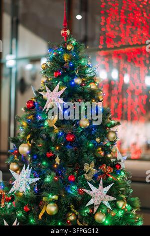 Schmückter Weihnachtsbaum mit bunten Lichtern und Ornamenten in einer festlichen Innenraumgestaltung Stockfoto