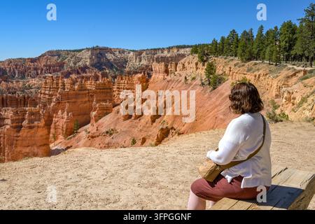 Bryce Canyon Nationalpark, Utah, USA - 29. Juni 2026: Person sitzt auf einer Holzbank und betrachtet die spektakulären Felsformationen des Bryce Canyon. Stockfoto