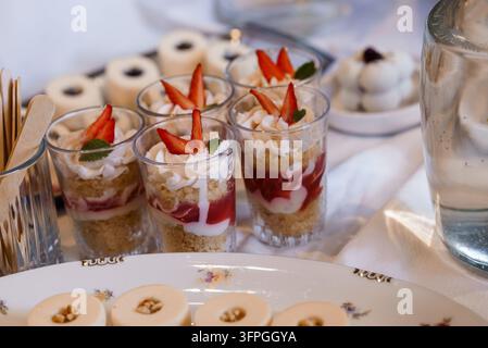 Erfrischende Obstschichtdesserts, garniert mit frischer Minze auf einem weißen Tischtuch für Hochzeitscatering oder Gastgewerbefotografie Stockfoto