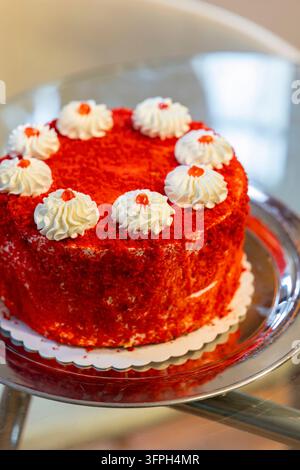 Red-Velvet-Kuchen auf einem Silbertablett, mit Schlagsahne und rotem Sirup überzogen Stockfoto