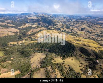 Weitläufige Luftaufnahme von sanften Hügeln, Ackerland, Wäldern und sich windenden Landstraßen in der Nähe von Cunha im Bundesstaat São Paulo, Brasilien. Stockfoto