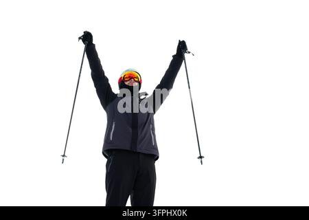 Skifahrer. Skifahrer, der zum Jubel die Skistöcke auf einem verschneiten Berggipfel hebt, ausgeschnitten. Skifahrer mit Skistöcken Stockfoto
