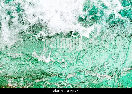 Blaue Wasseroberfläche, Wassertextur, Schaumblasen, Meerwasserhintergrund, Ozeanhintergrund, Schwimmbad, Wellenmuster, Spritzer, abstrakte Strombewegung Stockfoto
