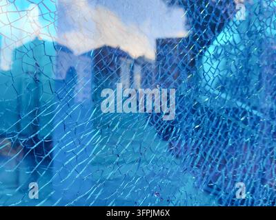 Eine Nahaufnahme von zerschmettertem blauem Sicherheitsglas mit einem komplexen Netz von Rissen, das Konzepte von Schaden, Eindringling, Verletzlichkeit und Sicherheit veranschaulicht Stockfoto