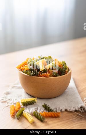 Trockenes tricolor Fusilli-Nudelgericht in einer Schüssel auf Holztablett Stockfoto