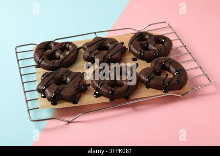 Schokoladen Lebkuchen. Oberansicht von Lebkuchenbrezeln auf einem Kühlrost auf blauem und rosa Hintergrund. Schokoladen Lebkuchen Stockfoto