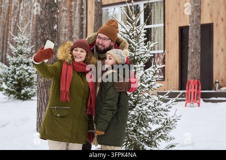 Glückliche Familie macht Selfie auf dem Smartphone während des Winterurlaubs Stockfoto