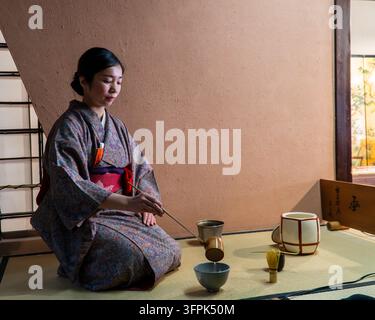 Japanische Teeceremonie mit einer Frau in einem traditionellen Kimono in einem Tatami-Raum in Kyoto, Japan. Stockfoto