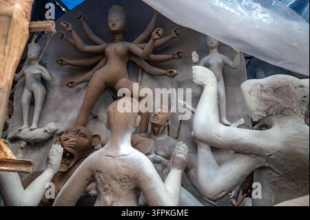 Durga Puja beeinflusst die Wirtschaft, Kultur und Umwelt von Westbengalen erheblich. Die Idole der Göttin Durga werden durch einen traditionellen Tonbildhauprozess gefertigt, der Monate vor dem Festival beginnt. Kunsthandwerker verwenden Alluvialton aus Flussbetten (hier der Jalngi-Fluss), schichten ihn auf eine Strohstruktur, um den Sockel der Statue zu bilden. Die Idole werden dann in Werkstätten innerhalb der Töpferkolonie im Rahmen der Festivalvorbereitungen bemalt. Aufgrund von Zeitdruck und einem Mangel an Kunsthandwerkern beteiligen sich alle in der Töpferkolonie – einschließlich verheirateter Frauen und Kinder, die normalerweise nicht an solchen Aktivitäten teilnehmen Stockfoto