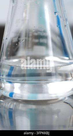 Erlenmeyerkolben mit klarer Flüssigkeit und Wassertropfen auf dem Glas, chemische Analyse im Labor Stockfoto