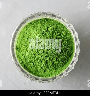 Zerteilte Chlorella oder Spirulina in einem Glasbecher auf grauem Beton. Oberblick. Stockfoto