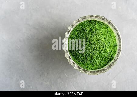 Zerteilte Chlorella oder Spirulina in einem Glasbecher auf grauem Beton. Oberblick. Stockfoto