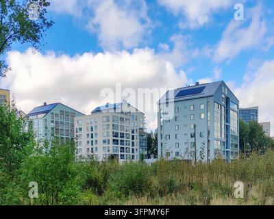 Moderne Mehrfamilienwohnbauten mit Solarmodulen auf den Dächern, gelegen in Finnoo, Espoo, Finnland, umgeben von Grasflächen unter einem b Stockfoto